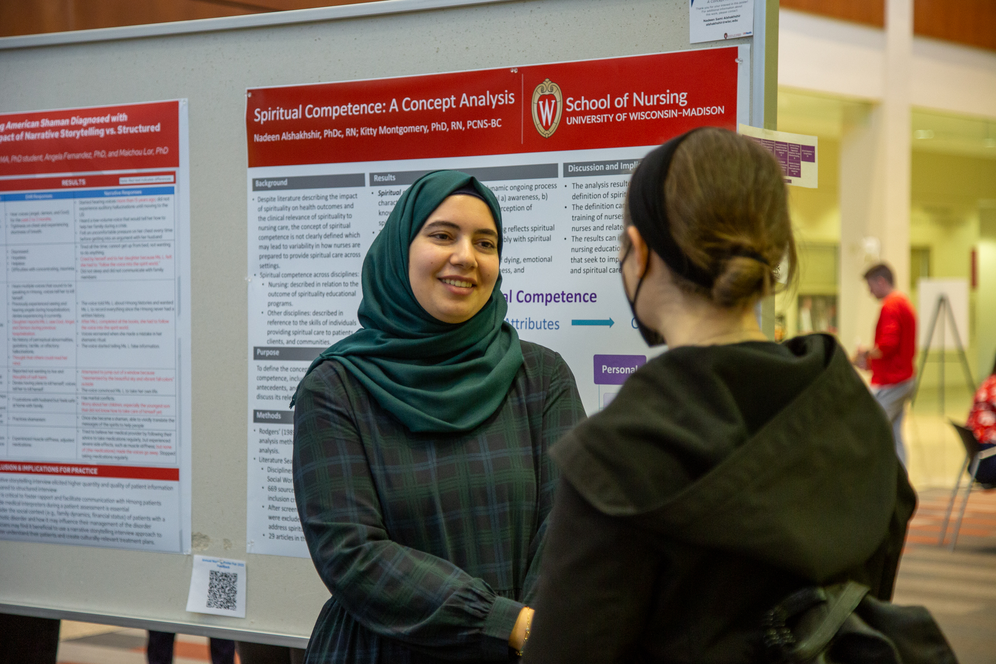 Montgomery's lab member smiling as she presents a poster presentation to a guest.