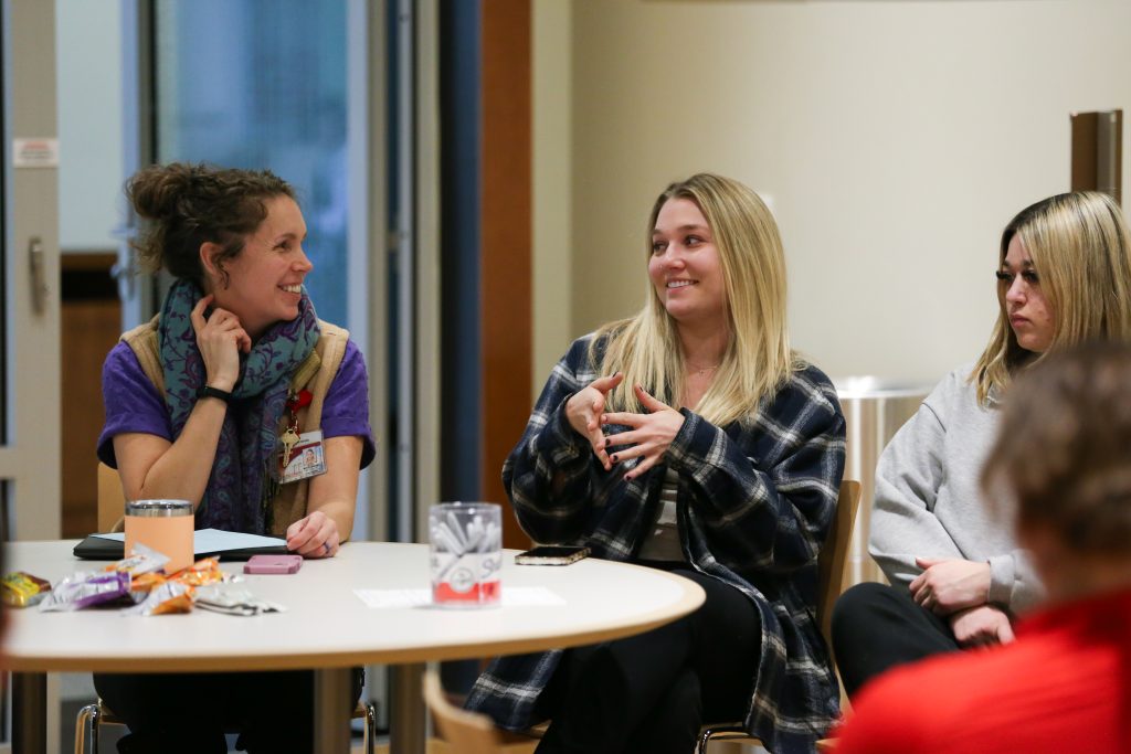 Dr. Kitty Montgomery smiling as she speaks with students at a round table.